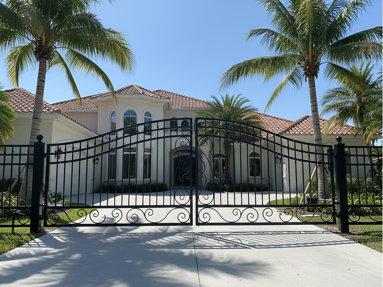 Black aluminum estate gate in front of a large home
