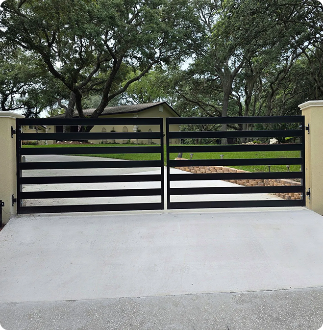 Black horizontal slat driveway gate under oak trees