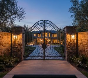 Arched wrought iron gate lit at night