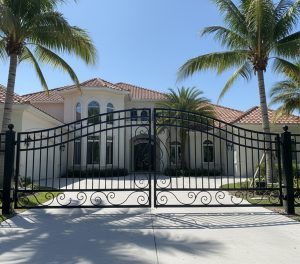 Black aluminum estate gate in front of a large home