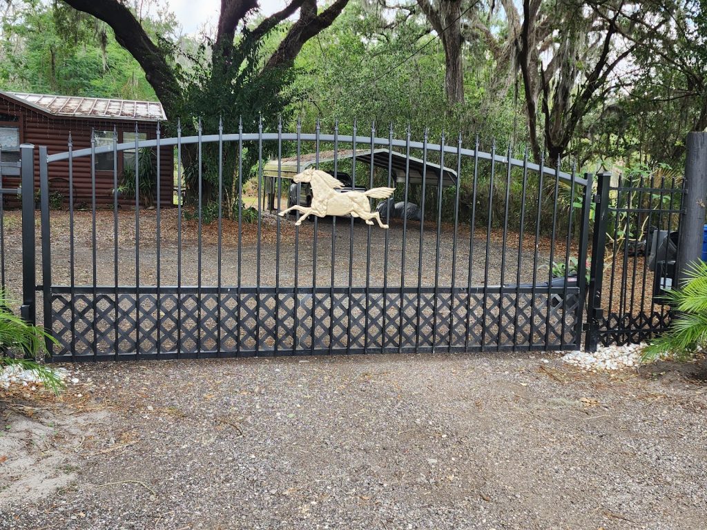 Arched ornamental iron-style driveway gate with a custom horse accent